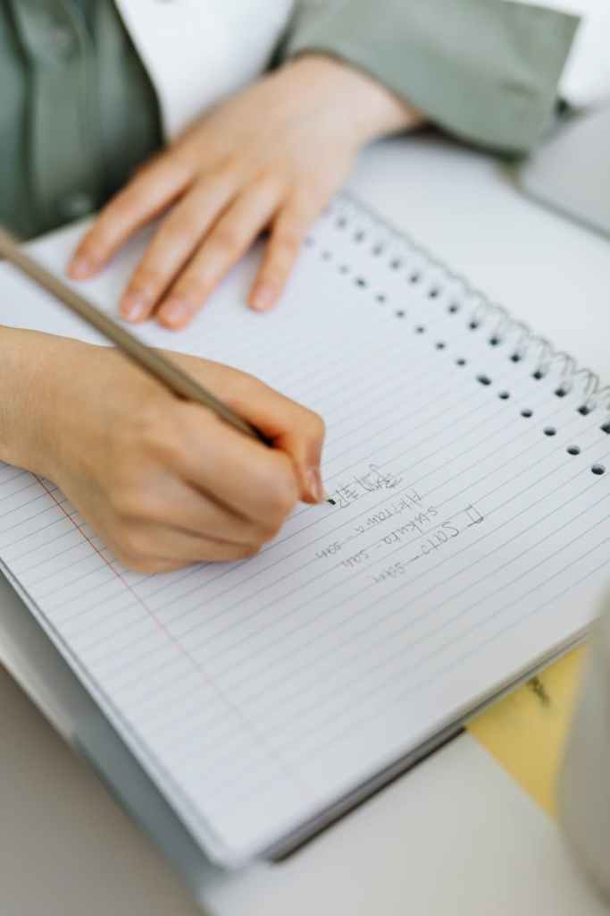 Stock image of someone writing in an a4 lined notebook.