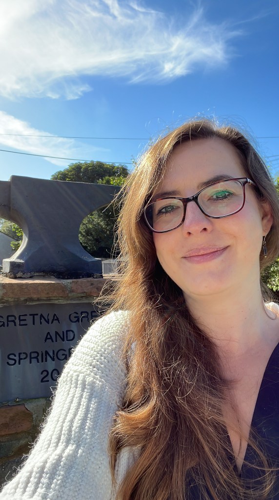 Photo of Hannah in Scotland next to the anvil in Gretna Green.